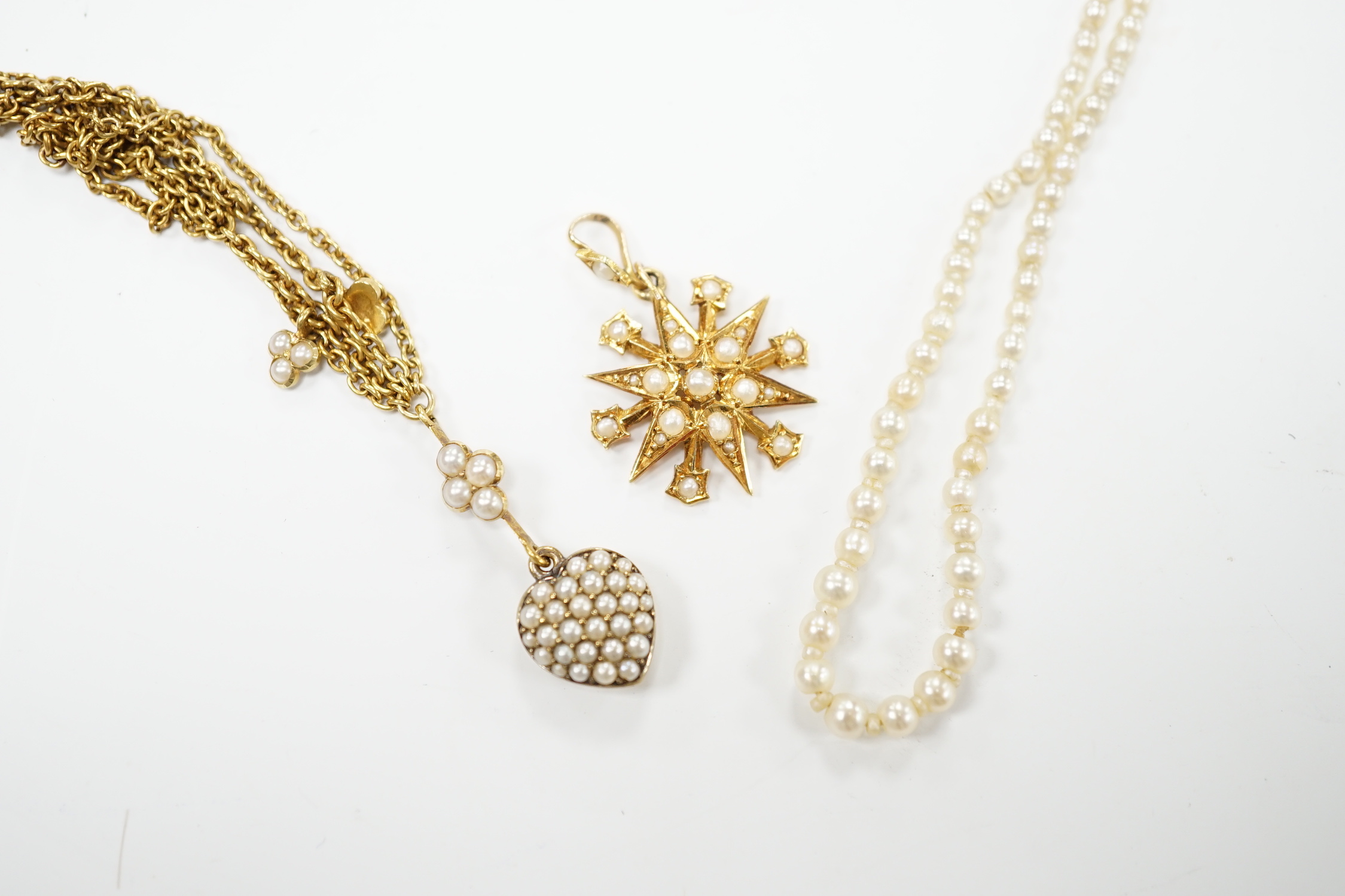 An Edwardian 15ct gold and seed pearl set starburst pendant, overall 25mm, together with a similar yellow metal and seed pearl set heart shaped drop pendant necklace, approx. 38cm (twisted) and a seed pearl necklace with